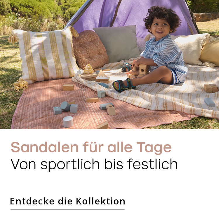 Zufriedener Junge auf einet Picknick Decke mit Sandalen von Dosenbach