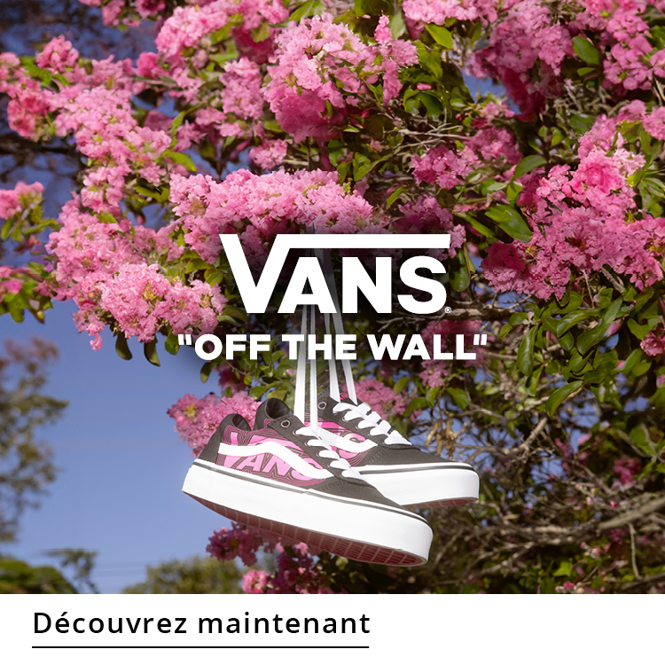 Sneakers Vans suspendues devant un buisson de fleurs