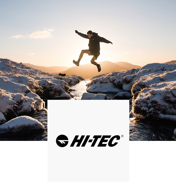 Man jumping outdoors over a stream in hi-tec shoes