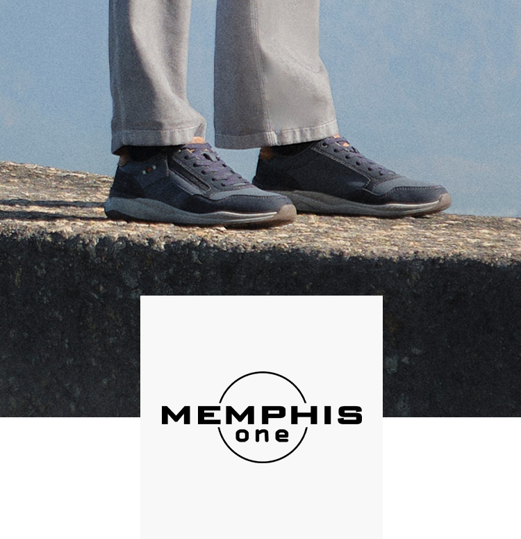 Man on a concrete wall with mountains in the background wearing memphis one shoes